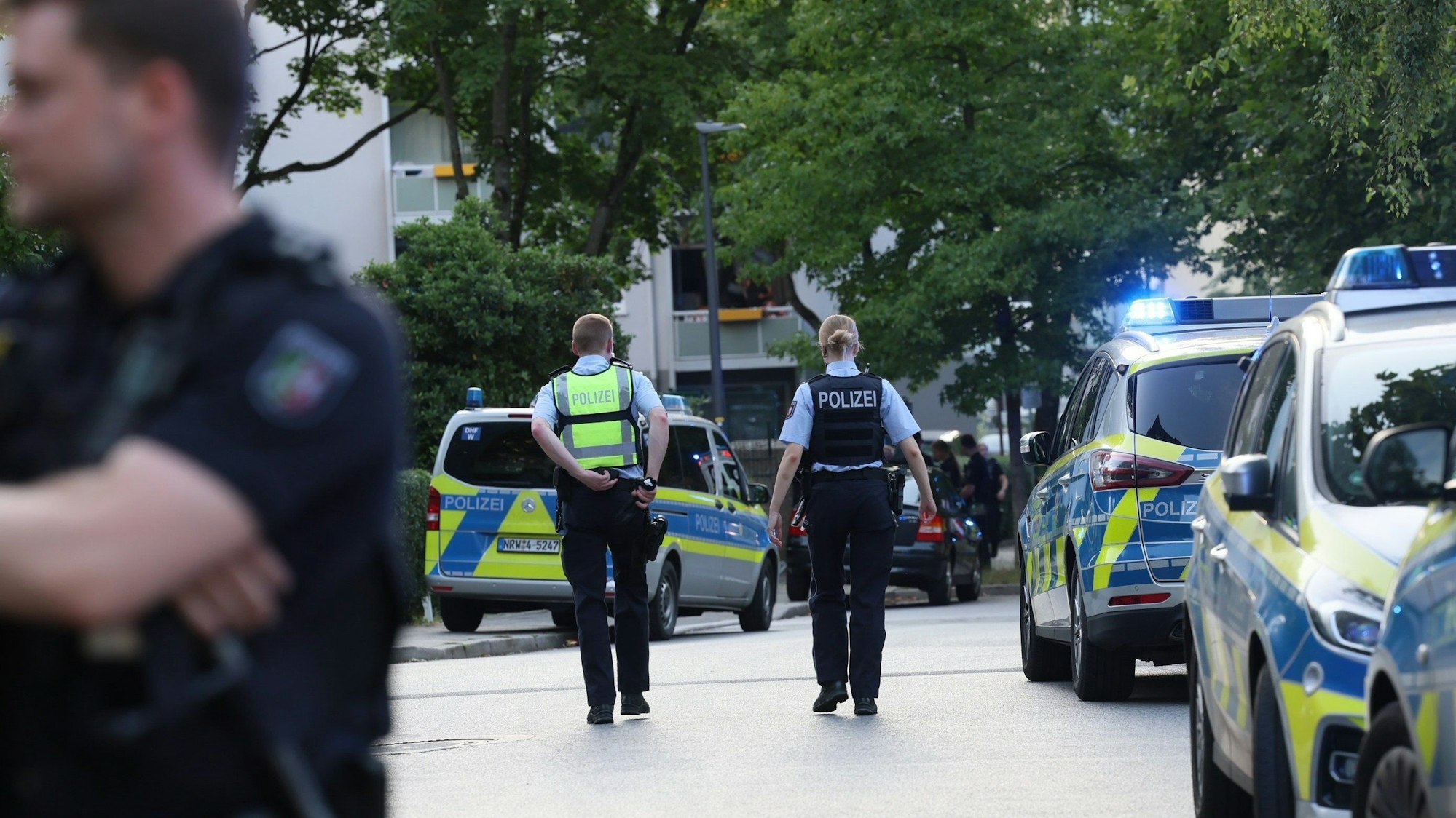 Streifenwagen der Polizei stehen in einem Wohngebiet auf der Straße.