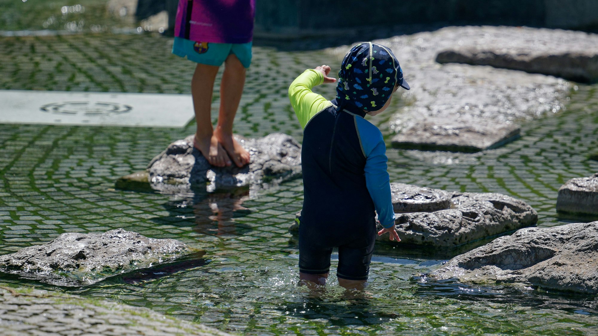Seit Tagen wird es wärmer und wärmer in Köln: Kinder kühlen sich in einem Brunnen nahe des Rheins ab.