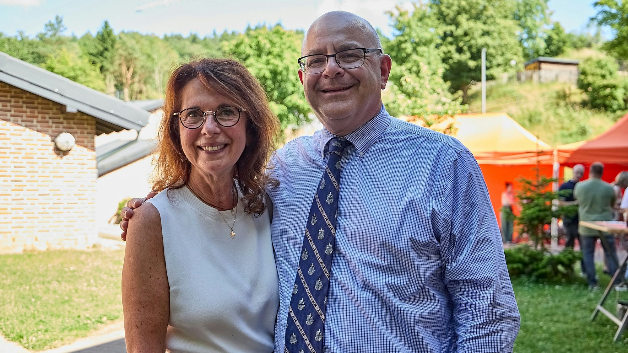 Roswitha Schütt-Gerhards und James De Angelo stehen Arm in Arm auf einer Wiese. Sie feiern das Jubiläum des Austauschs zwischen Schleiden und den USA.