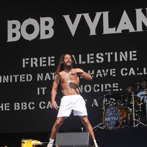 Ein Bob Vylan-Musiker steht beim Auftritt während des Glastonbury Festivals vor dem Schriftzug „Free Palestine – United Nations have call it a genocide“. Zwei Bands haben die Bühne des weltbekannten Festivals für antiisraelische Parolen und Kritik an der britischen Regierung genutzt.