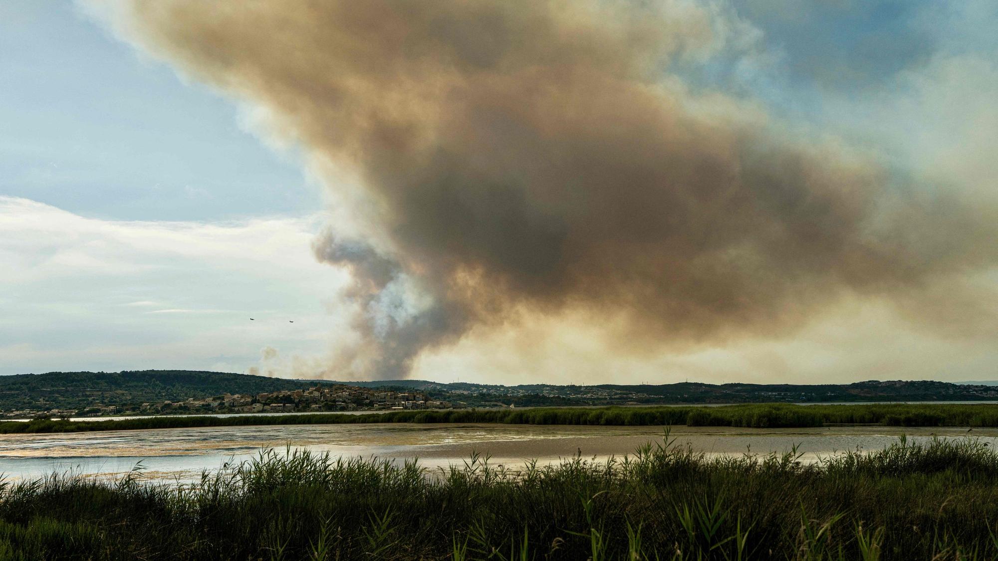 29.06.2025, Frankreich, Bizanet: Dieses Foto zeigt zwei Löschflugzeuge, die westlich der Stadt Narbonne im Südwesten Frankreichs, in der Nähe einer Rauchfahne, verursacht durch einen Waldbrand, an einem Berghang fliegen. Ein Teil des Corbières-Gebirges steht in Flammen, so dass die Abtei Fontfroide und ein Campingplatz vorsorglich evakuiert werden mussten, wie die Präfektur und die Feuerwehr des Departements mitteilten. Foto: Idriss Bigou-Gilles/AFP/dpa +++ dpa-Bildfunk +++