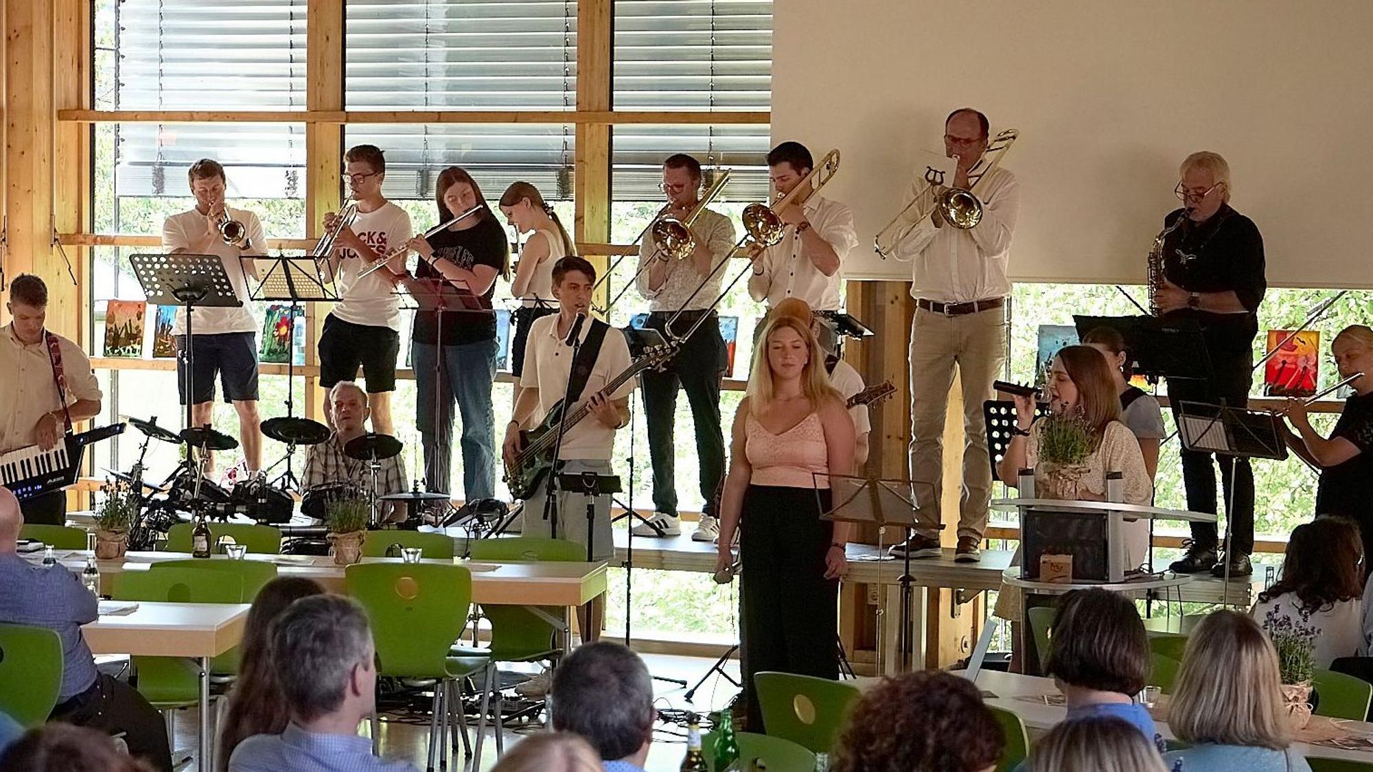 Die Band „Fettes C“ steht auf einer Bühne in der Mensa der Clara-Fey-Schule in Schleiden.