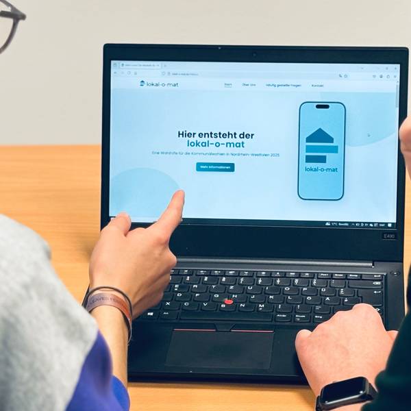 Zwei Menschen blicken auf einen Computer-Bildschirm.