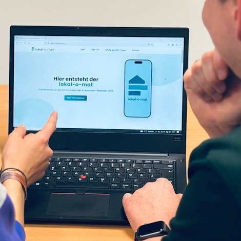 Zwei Menschen blicken auf einen Computer-Bildschirm.