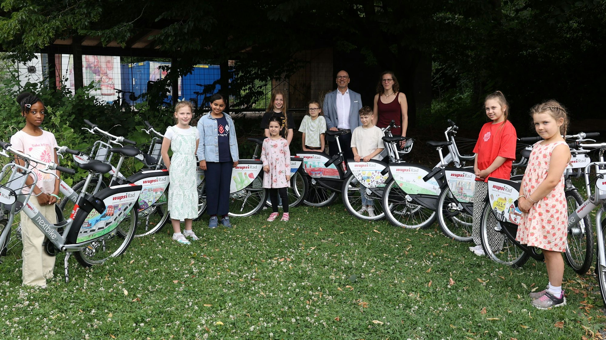 Kinder stehen vor Fahrrädern, die mit ihren Bildern bedruckt wurden
