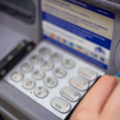 Ein Bankkunde steckt eine Girokarte in einen Geldautomaten.