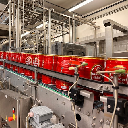 Ein Mann steht in einem Foyer neben dem Firmenschild Kölner Brautradition Seit 1894.