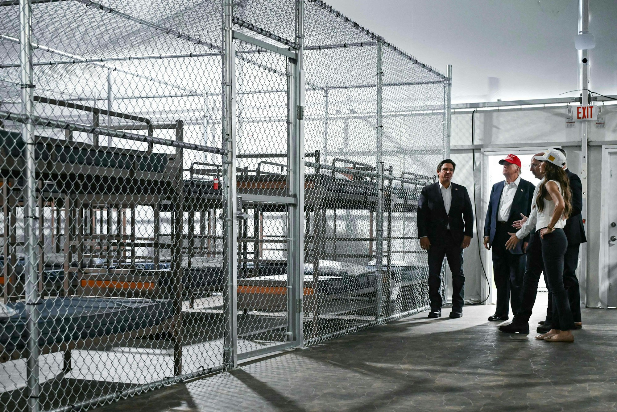 TOPSHOT - US President President Donald Trump (2L), Florida Governor Ron DeSantis (L), and Secretary of Homeland Security Kristi Noem (R) tour a migrant detention center, dubbed "Alligator Alcatraz," located at the site of the Dade-Collier Training and Transition Airport in Ochopee, Florida on July 1, 2025. President Trump is visiting a migrant detention center in a reptile-infested Florida swamp dubbed "Alligator Alcatraz." Trump will attend the opening of the 5,000-bed facility -- located at an abandoned airfield in the Everglades wetlands -- part of his expansion of deportations of undocumented migrants, his spokeswoman said. (Photo by ANDREW CABALLERO-REYNOLDS / AFP)