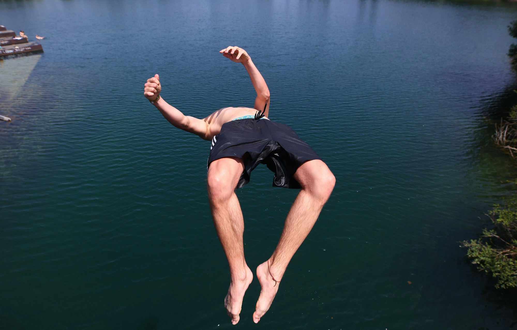 Ein junger Mann springt (verbotenerweise) von einer Brücke in den Fühlinger See. Köln erlebt Hitzetage mit Temperaturen von mehr als 30°C.