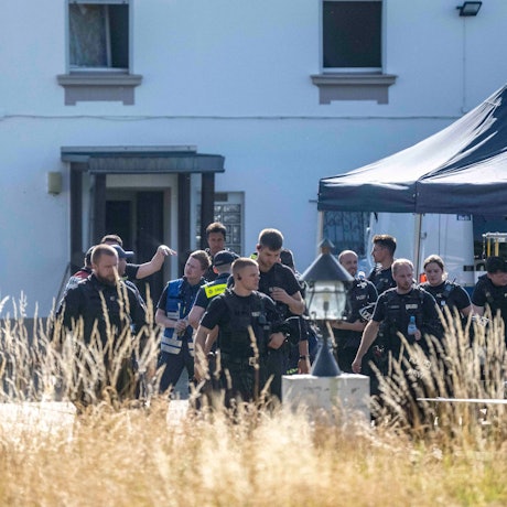 Das Bild zeigt einen Moment während der Razzia. Polizeibeamte und Mitarbeitende des THW befinden sich vor einem Haus.