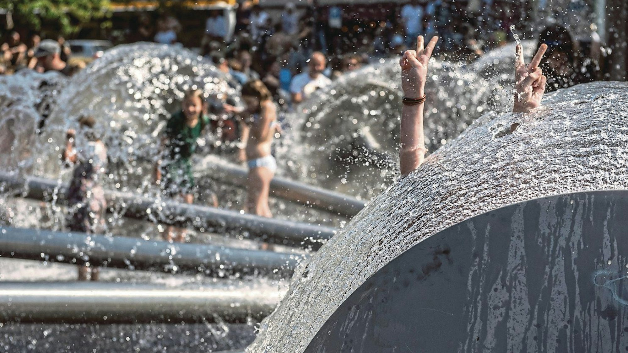 Der Brunnen am Ebertplatz sprudelt, Kinder spielen im Wasser.