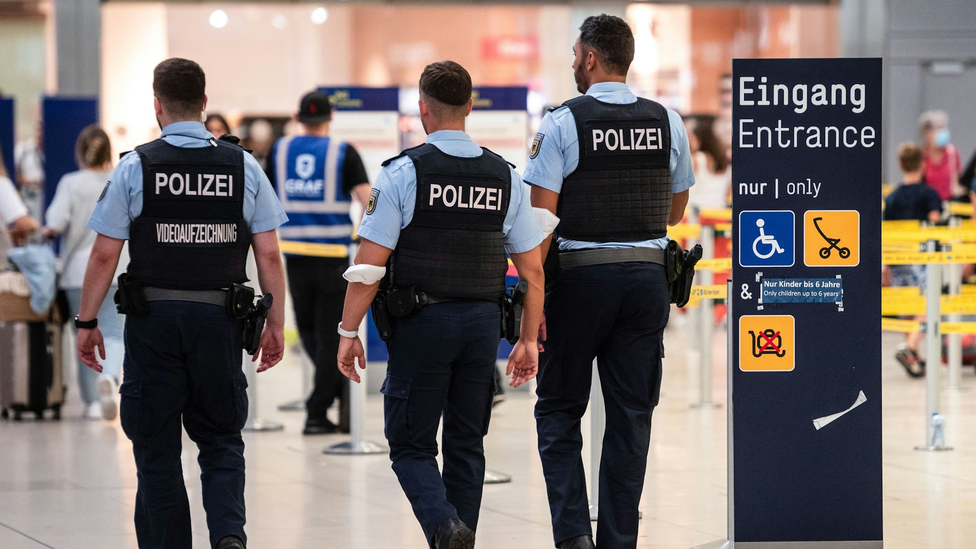 ARCHIV - 29.07.2022, Nordrhein-Westfalen, Köln: Beamte der Bundespolizei gehen an den Sicherheitskontrollen des Flughafens Köln/Bonn vorbei.  (zu dpa: «Mutmaßliche Kindergeld-Betrügerin am Flughafen festgenommen») Foto: Marius Becker/dpa +++ dpa-Bildfunk +++