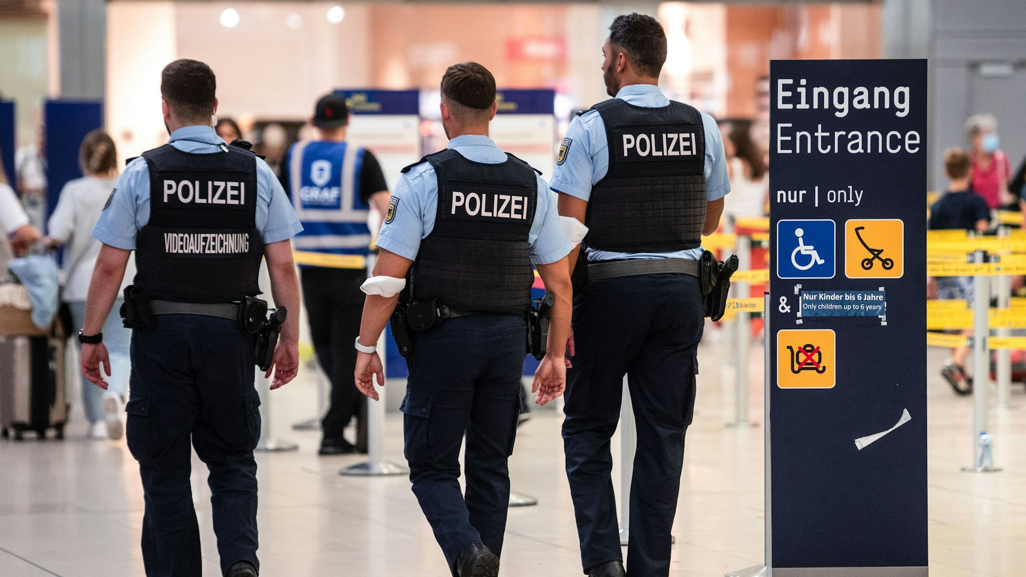 Drei Beamte der Bundespolizei gehen an den Sicherheitskontrollen des Flughafens Köln/Bonn vorbei.