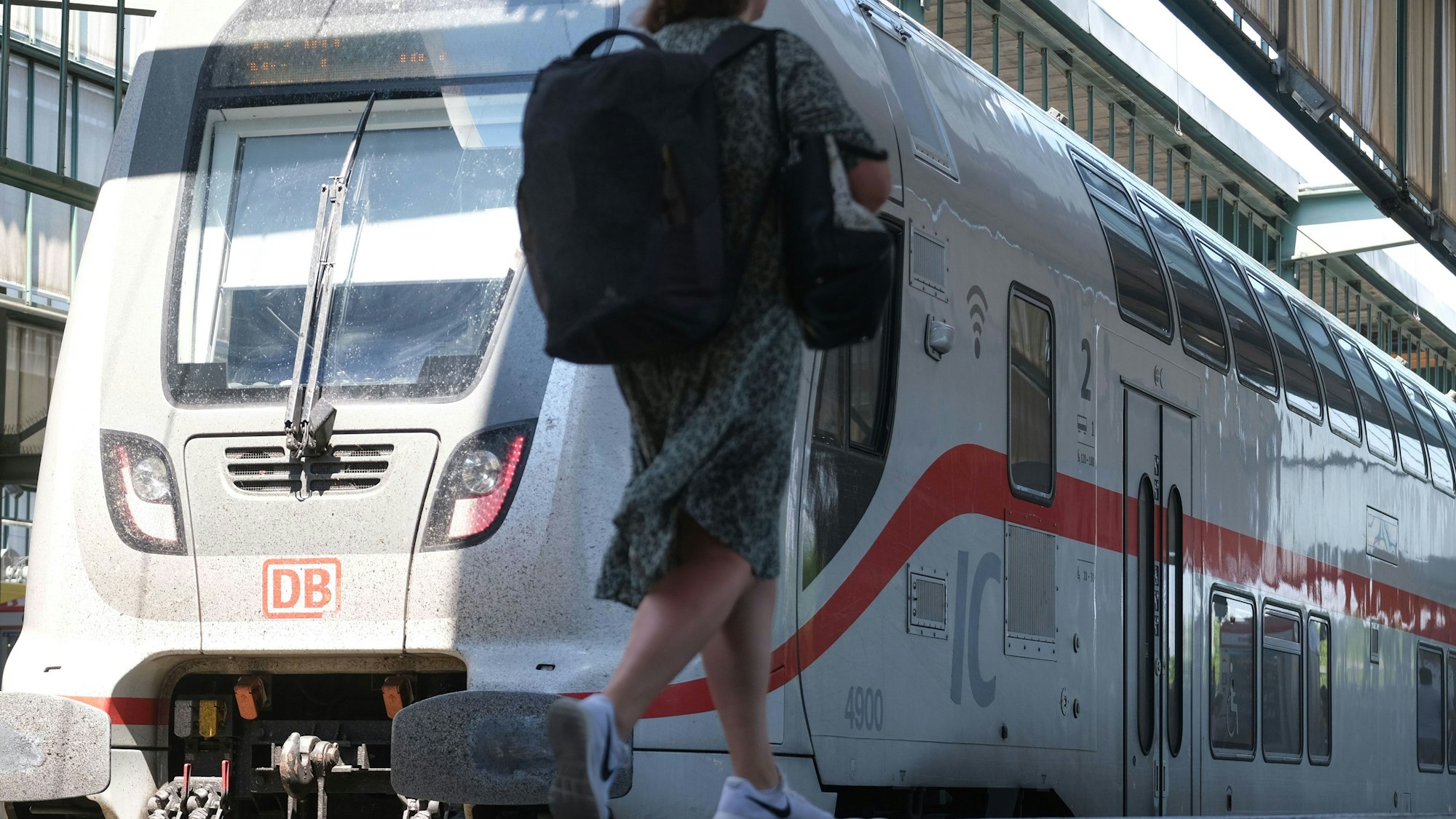 Eine Frau geht auf einem Bahnsteig im Hauptbahnhof zu einem IC Zug der Deutschen Bahn.