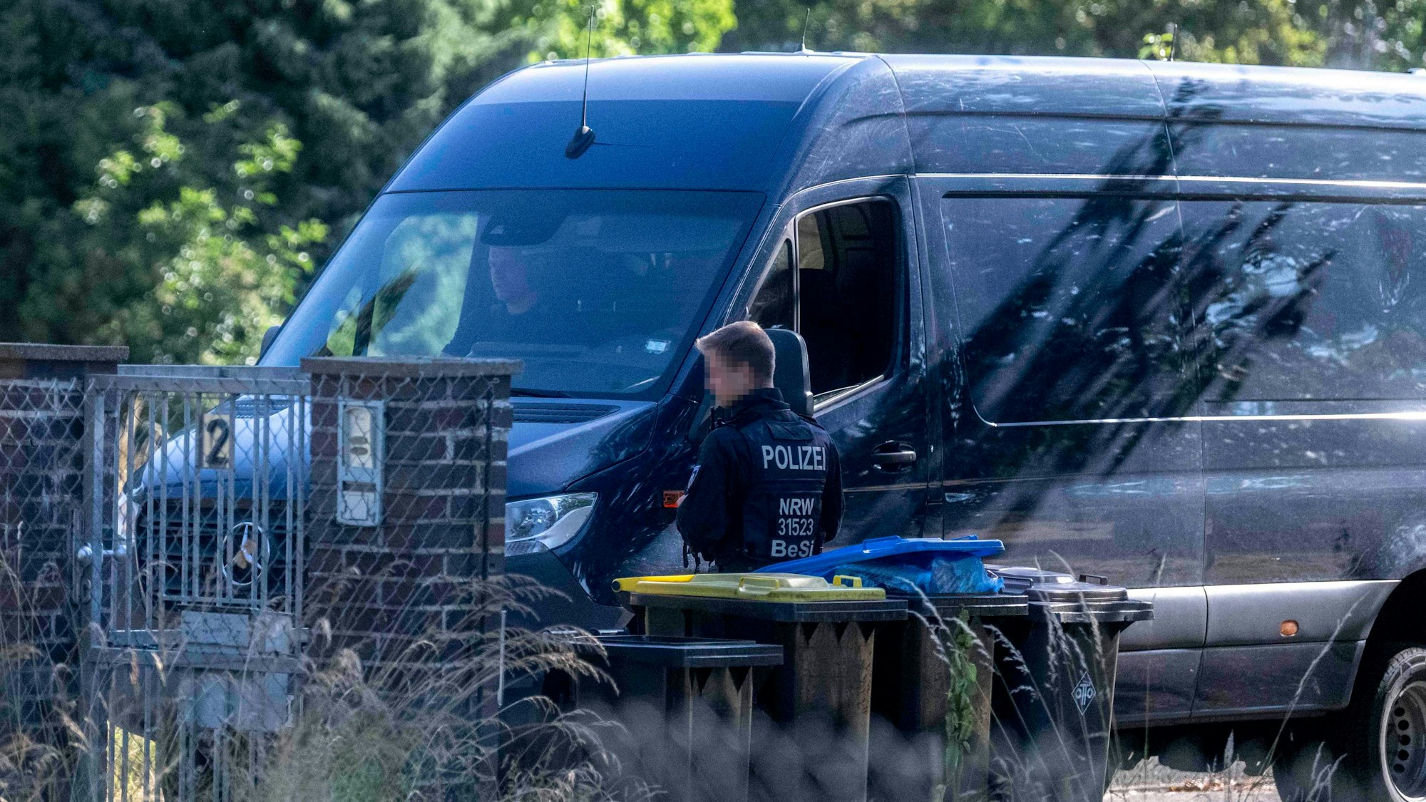 Ein Polizist in Uniform vor einem Transporter in Zivillackierung.