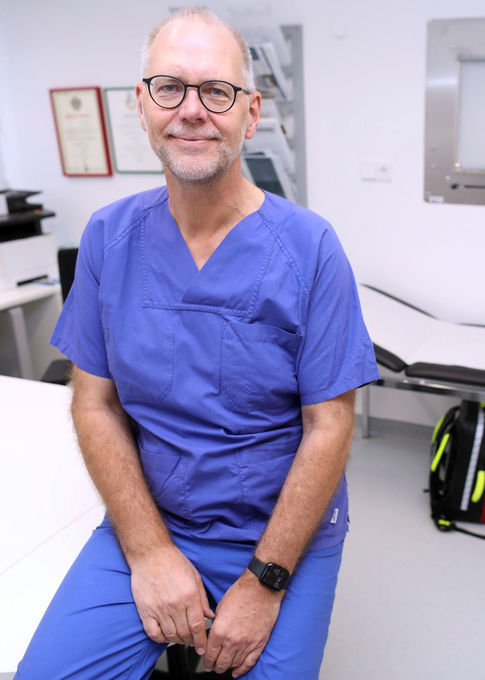Professor Arno Dormann ist in Arztkleidung in einem Behandlungszimmer zu sehen.