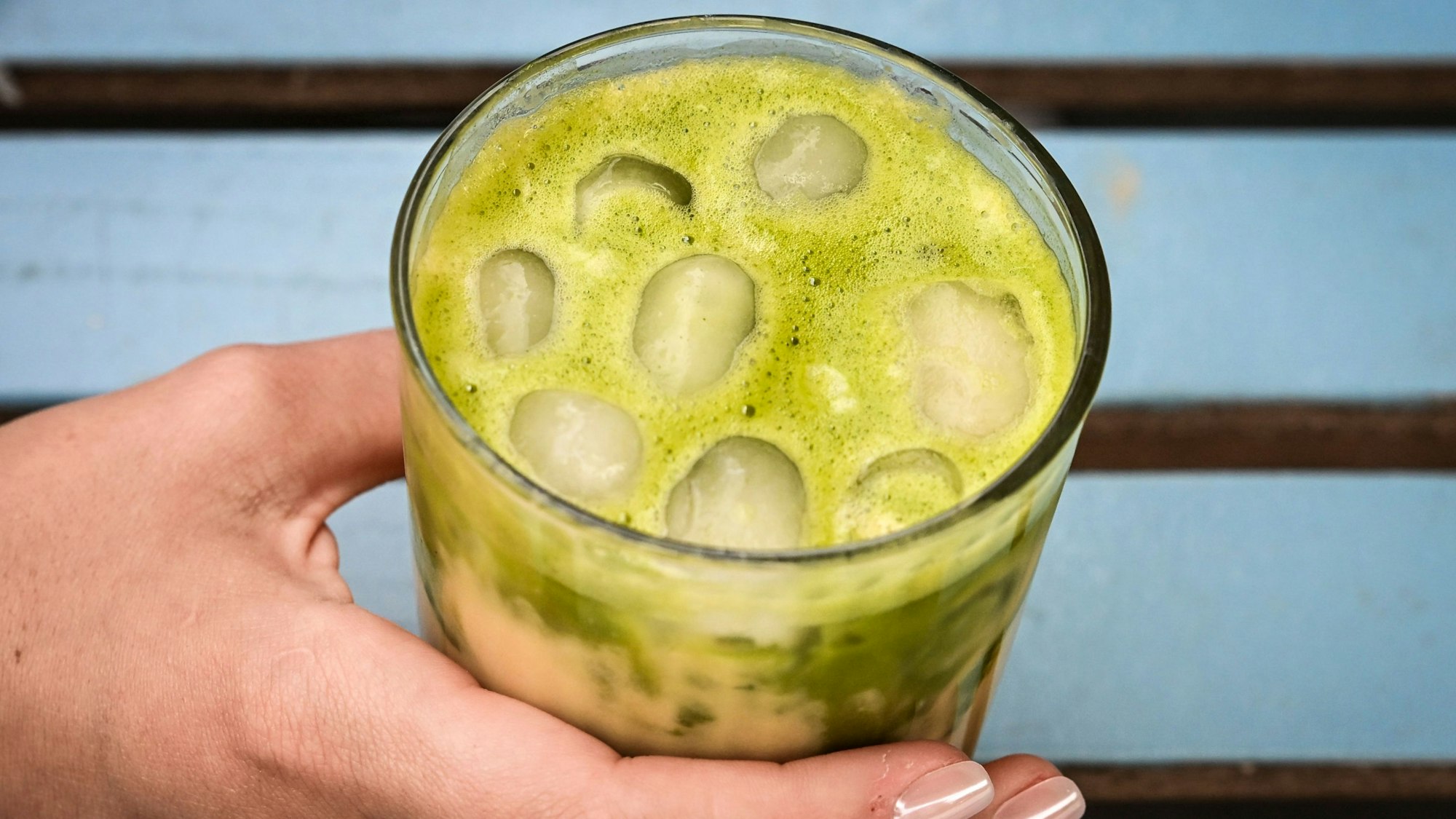 23.06.2025, Berlin: Eine junge Frau trinkt einen Iced Matcha Latte.