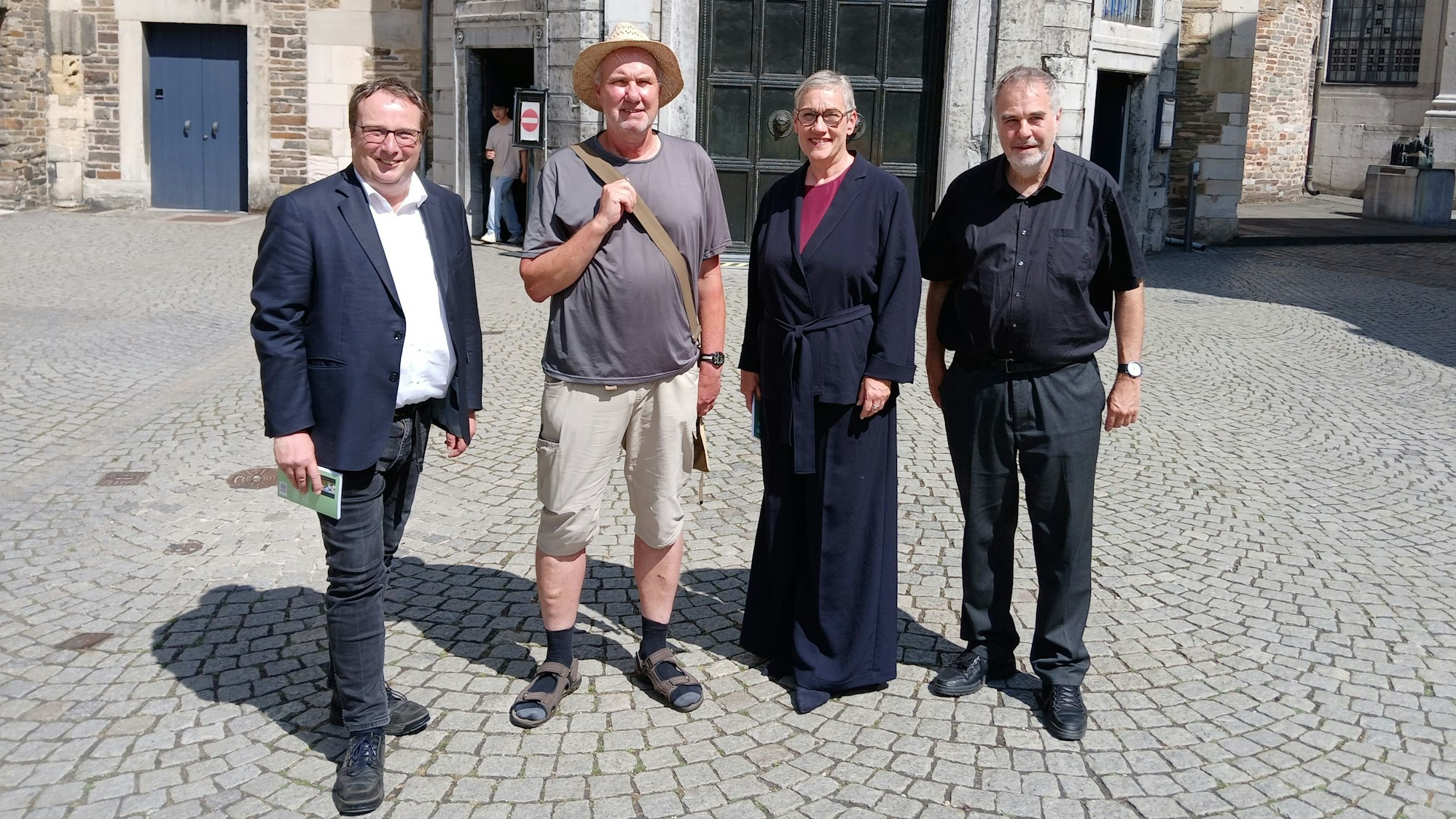 Vor der Aachener Dompforte stehen Oliver Krischer, Ralf Spilles, Sibylle Keupen und Rolf-Peter Cremer.
