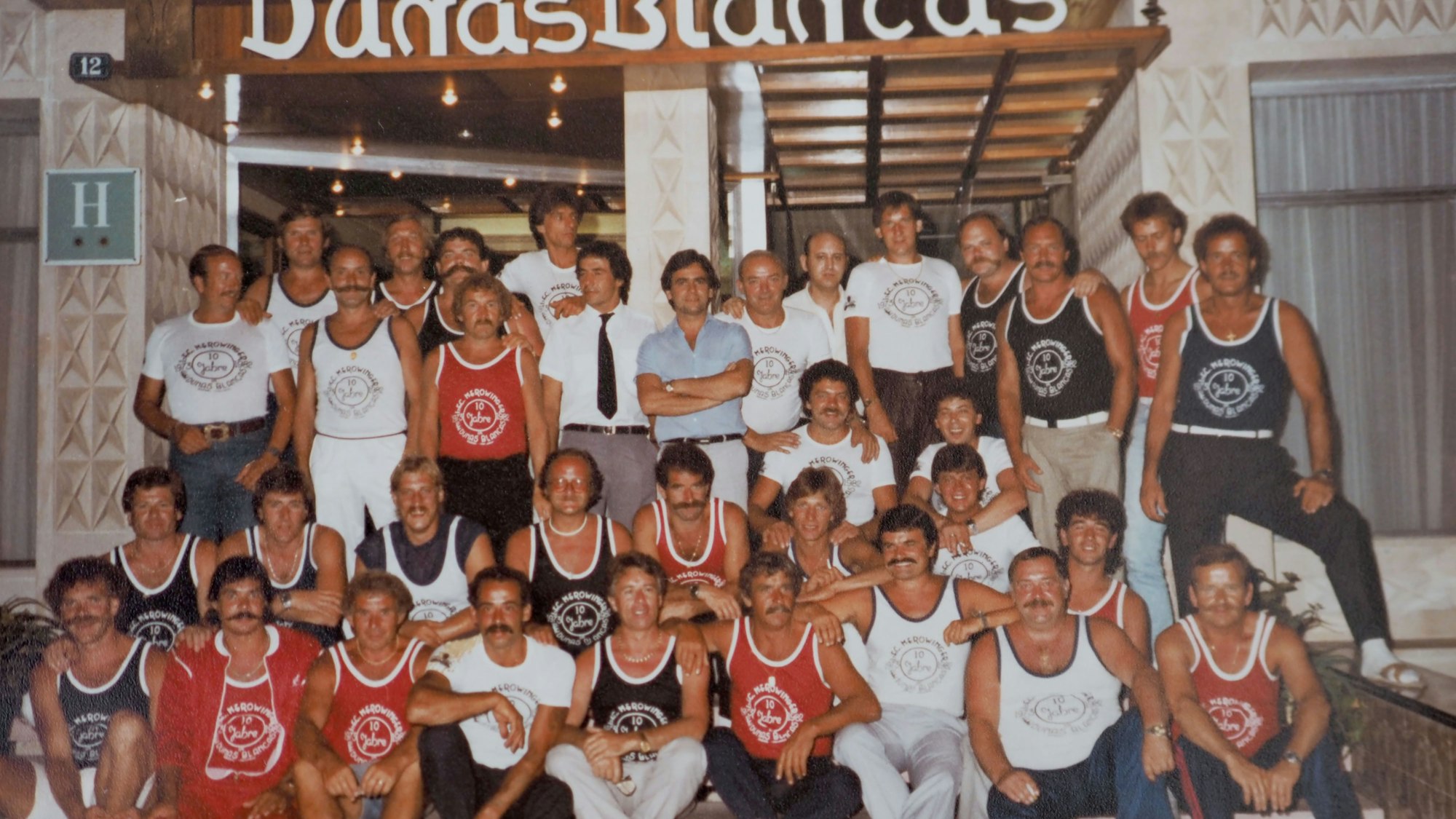 Werner Dive und andere Mitglieder des FC Merowinger stehen vor einem Hoteleingang