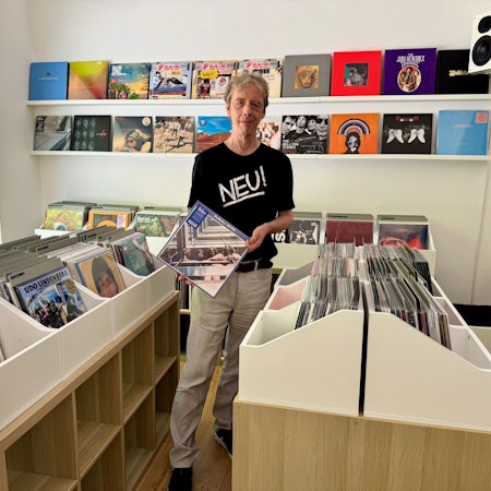 Auf dem Bild ist ein Mann mit einer Langspielplatte in der Hand zu sehen.