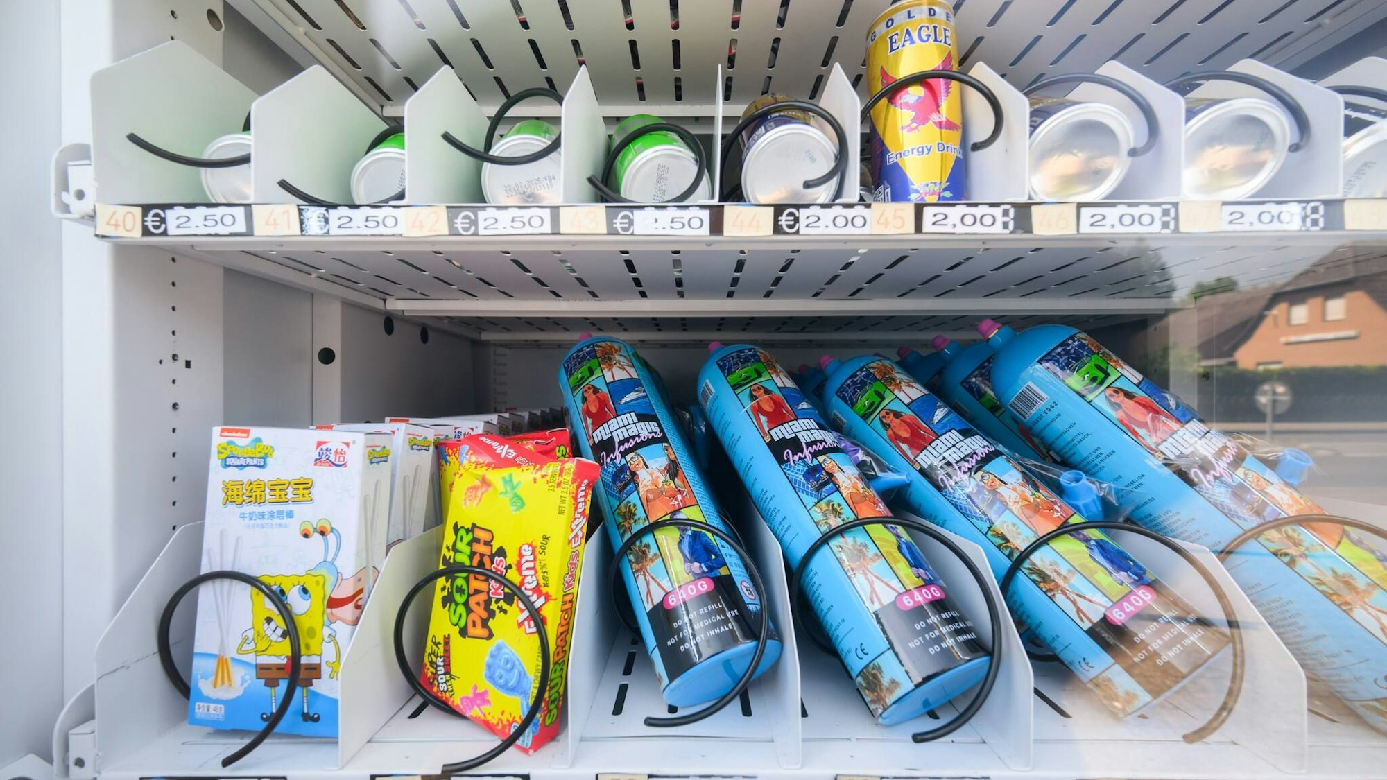 Ein Warenautomat, unter anderem mit Lachgasflaschen bestückt, steht vor einem Ladengeschäft. . Julian Stratenschulte