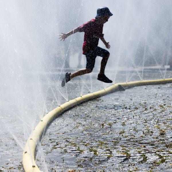 Ein Kind springt durch feinen Wassernebel. (Archivbild)