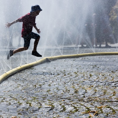 Ein Kind springt durch feinen Wassernebel. (Archivbild)