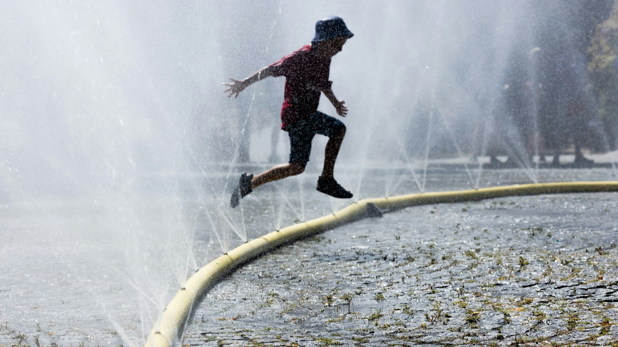 Ein Kind springt durch feinen Wassernebel. (Archivbild)