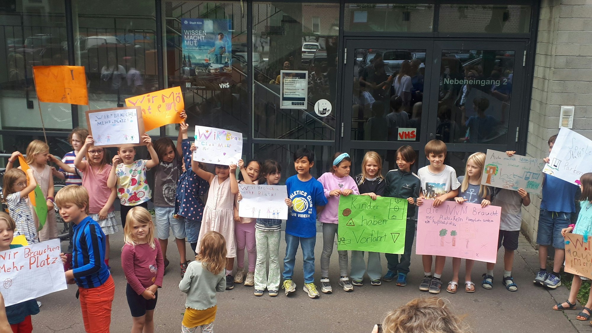 Zahlreiche Kinder demonstrieren mit selbstgebastelten bunten Plakaten für eine Erweiterung ihres Schulhofs