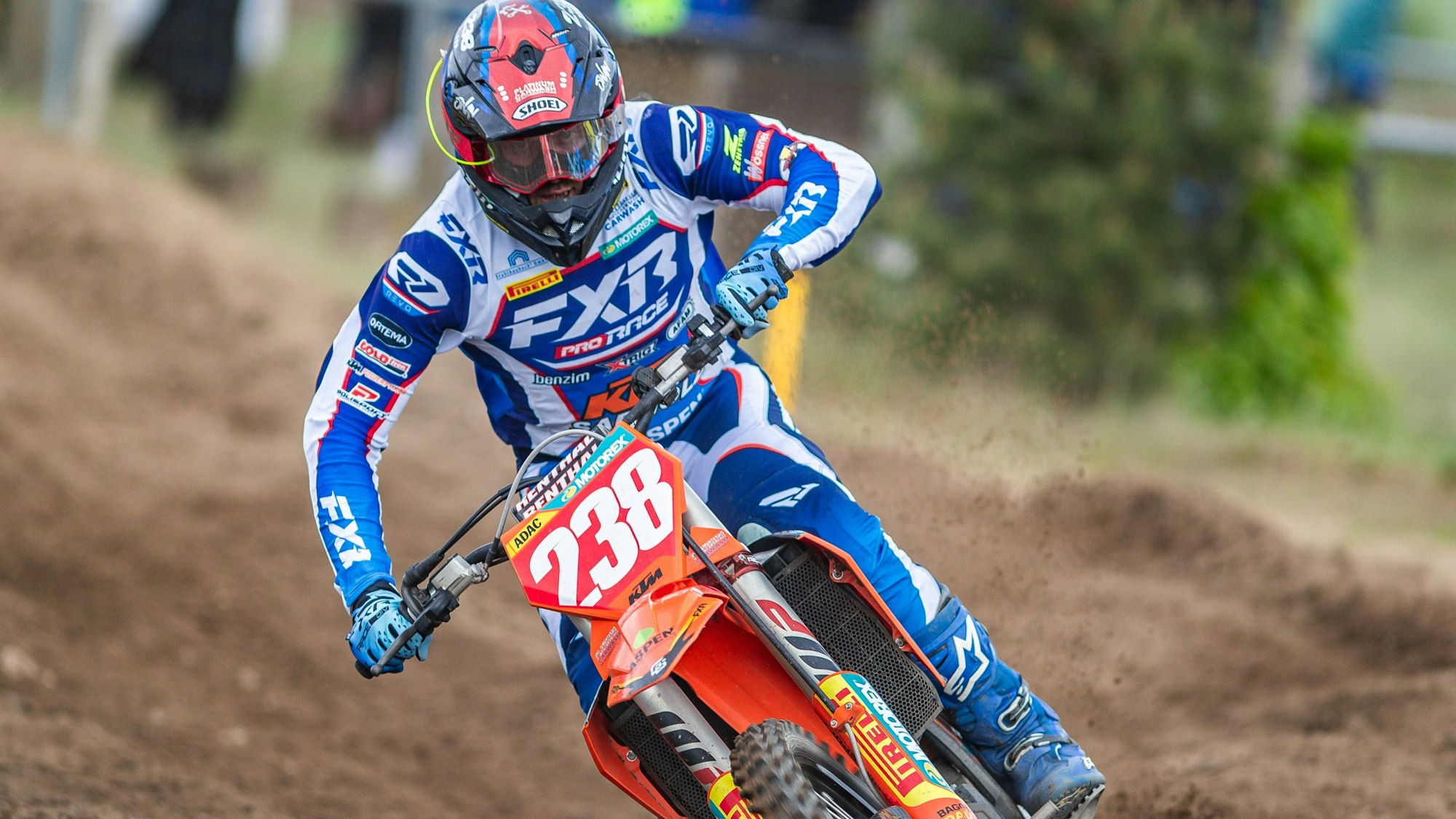 Zu sehen ist ein Motocross-Fahrer der durch den Schlamm fährt.