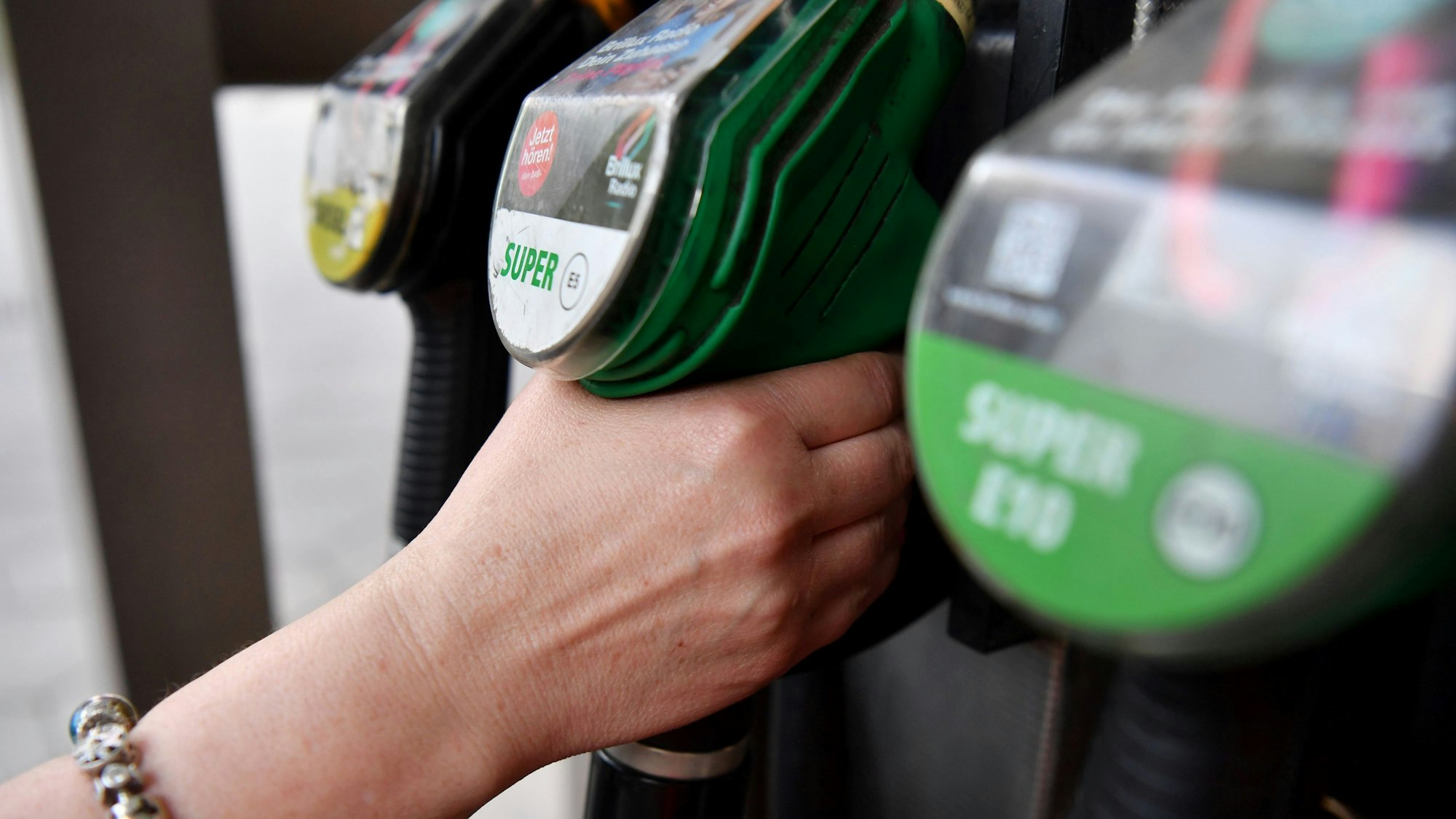 Eine Frau greift nach der Zapfpistole an einer Tankstelle.