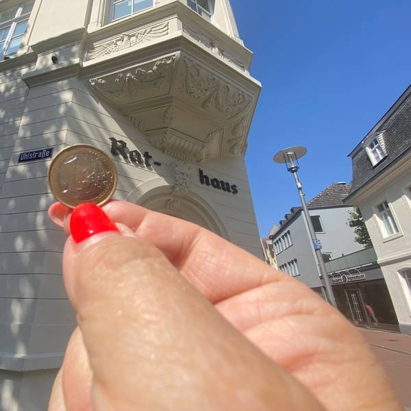 Zu sehen ist eine Ein-Euro-Münze und im Hintergrund das Brühler Rathaus.