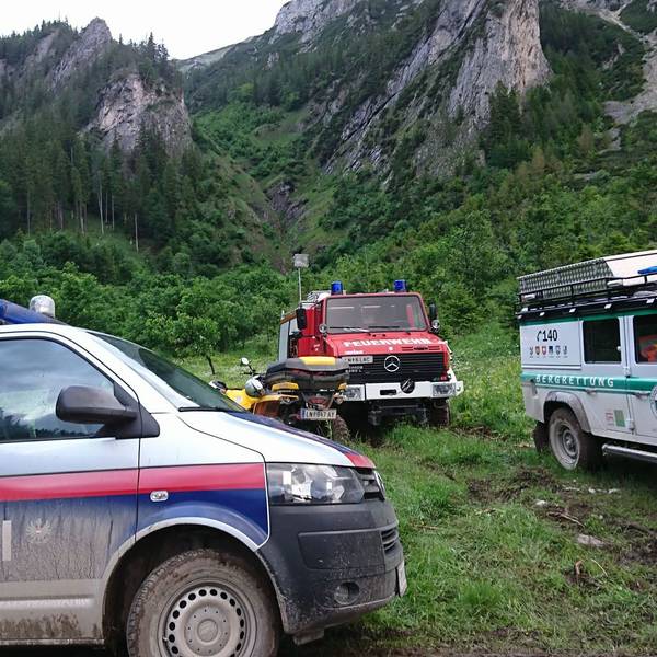 Einsatzfahrzeuge von Polizei, Feuerwehr und Bergrettung stehen am Berg.