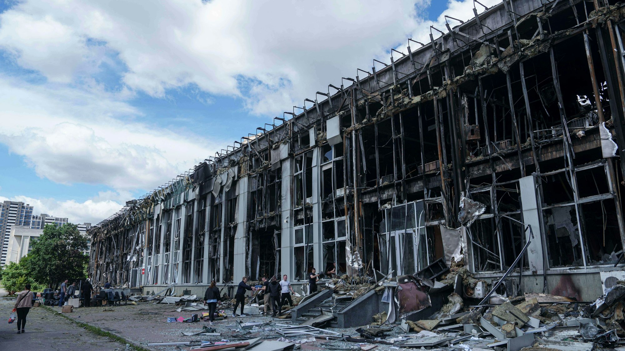 ARCHIV - 23.06.2025, Ukraine, Kiew: Menschen transportieren Habseligkeiten aus einem durch einen russischen Angriff zerstörten Bürogebäude in Kiew. (zu dpa: «Ukraine: UN-Generalsekretär für bedingungslose Waffenruhe») Foto: Evgeniy Maloletka/AP/dpa +++ dpa-Bildfunk +++