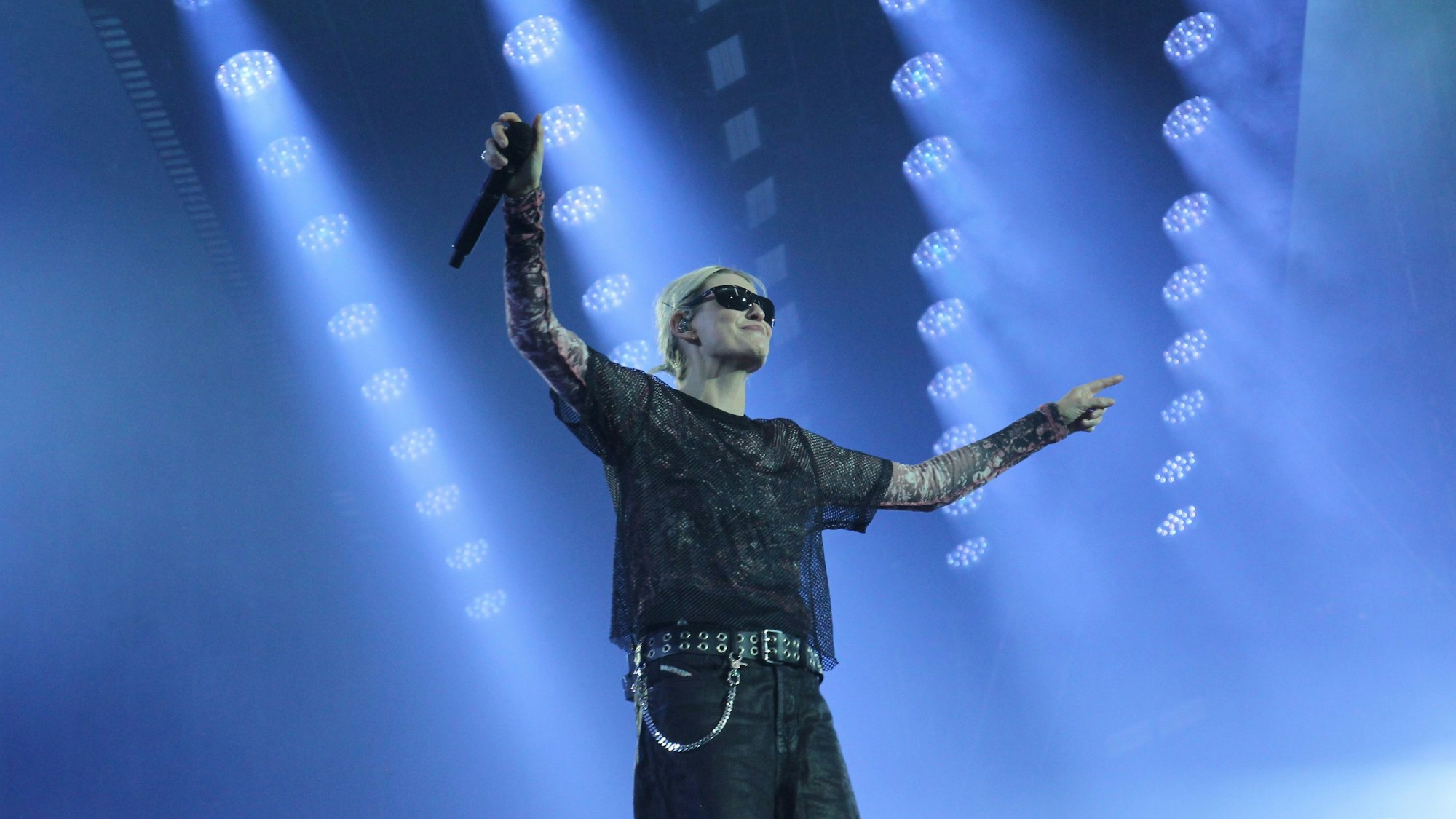 Die Sängerin Emily Armstrong von Linkin Park steht mit ausgebreiteten Armen auf der Bühne. Sie trägt eine Sonnenbrille.