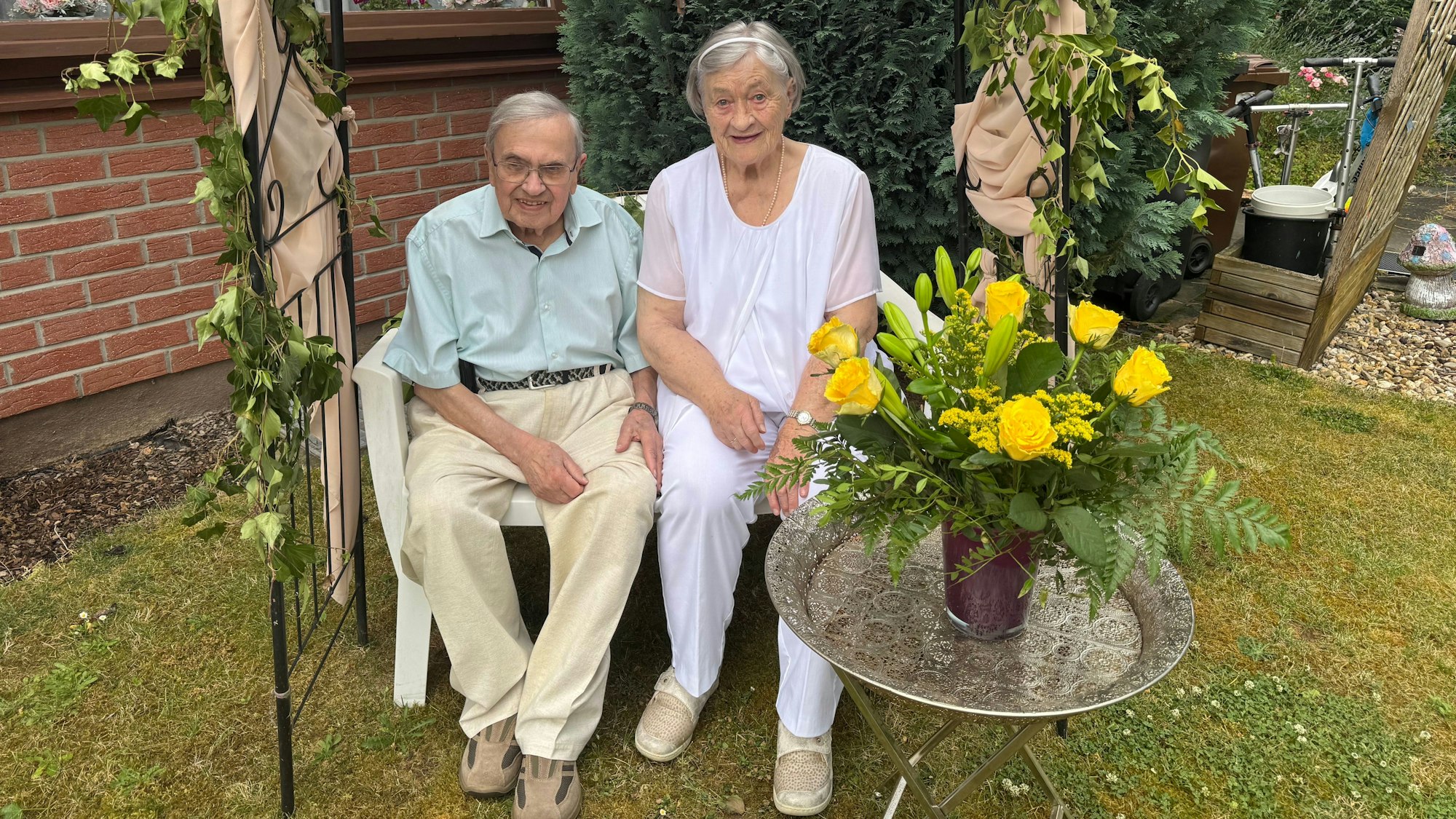 Ein älteres Ehepaar sitzt auf einer Bank im Garten.
