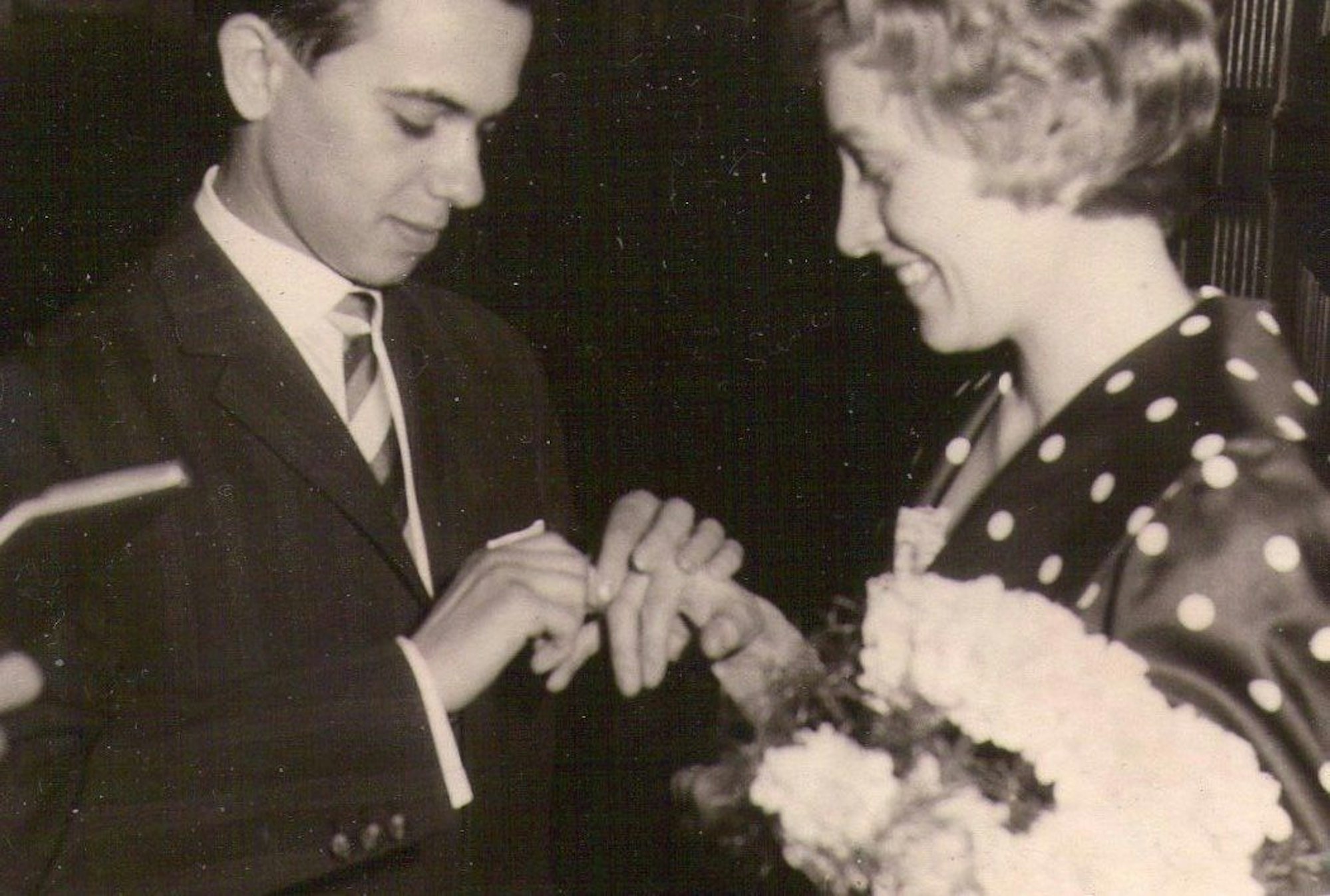 Ein Bräutigam steckt seiner Braut einen Ring an den Finger.