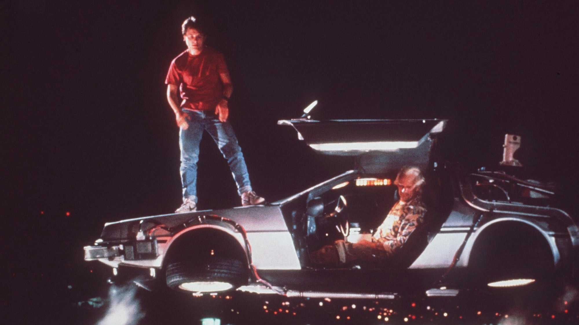 Michael J. Fox (als Marty McFly, l) und Christopher Lloyd (als Wissenschaftler Doc Brown) mit der Zeitmaschine, ein umgebauter Sportwagen vom Typ DeLorean DMC-12. In «Zurück in die Zukunft» wird der von Michael J. Fox verkörperte Held Marty McFly aus dem Jahr 1985 ins Jahr 1955 katapultiert.
