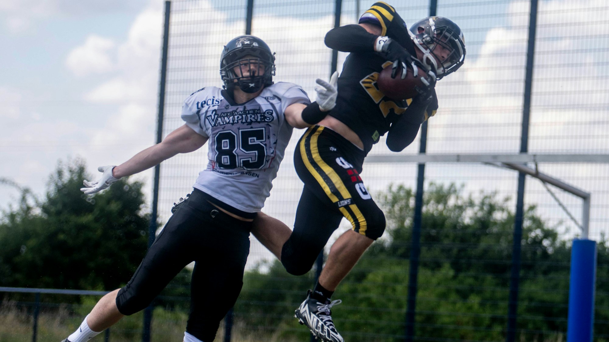 Footballspieler Fynn Handschke fängt einen Ball im Sprung, während ein Gegenspieler versucht, ihn aufzuhalten.