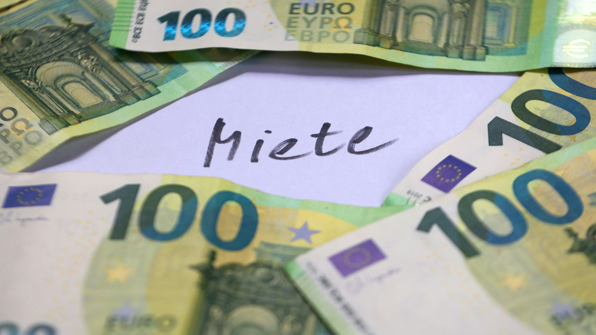 SYMBOLBILD - 03.06.2025, Bayern, Augsburg: 100-Euro-Banknoten liegen um das Wort «Miete». (zu dpa: «Mieterbund schlägt Alarm: Mieten werden zur Armutsfalle») Foto: Karl-Josef Hildenbrand/dpa +++ dpa-Bildfunk +++