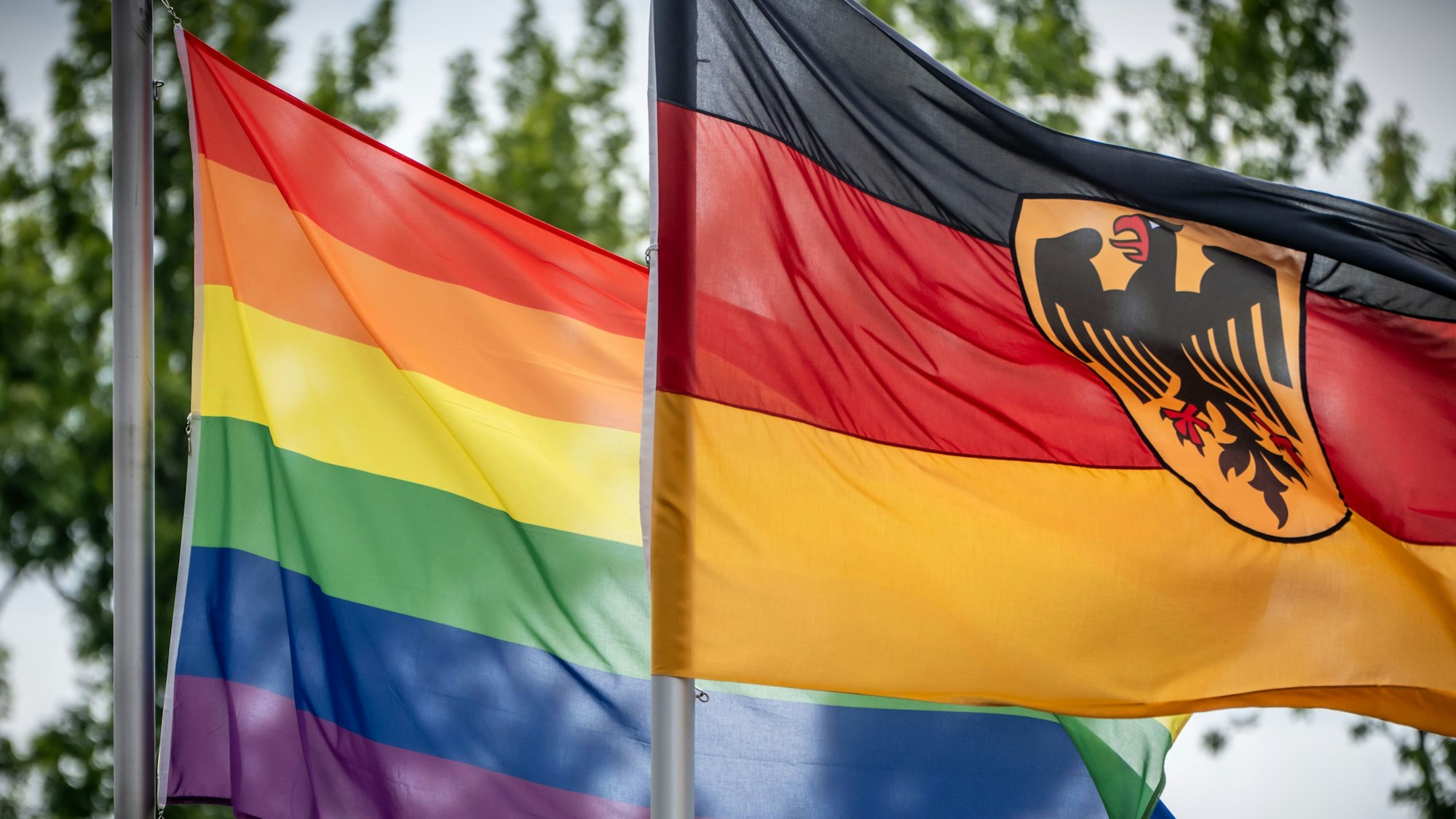 Das Bild zeigt eine Regenbogenflagge (l), die neben der Deutschlandfahne vor dem Bundesverteidiungsministerium weht. Foto: Michael Kappeler/dpa