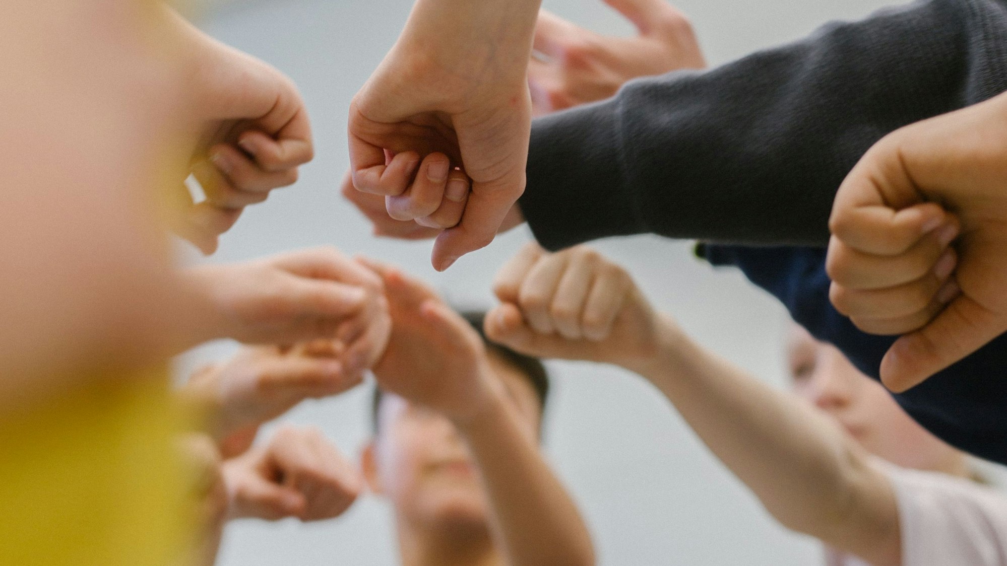 Mehrere Kinder halten ihre Fäuste als Zeichen des Zusammenhalts zusammen.
