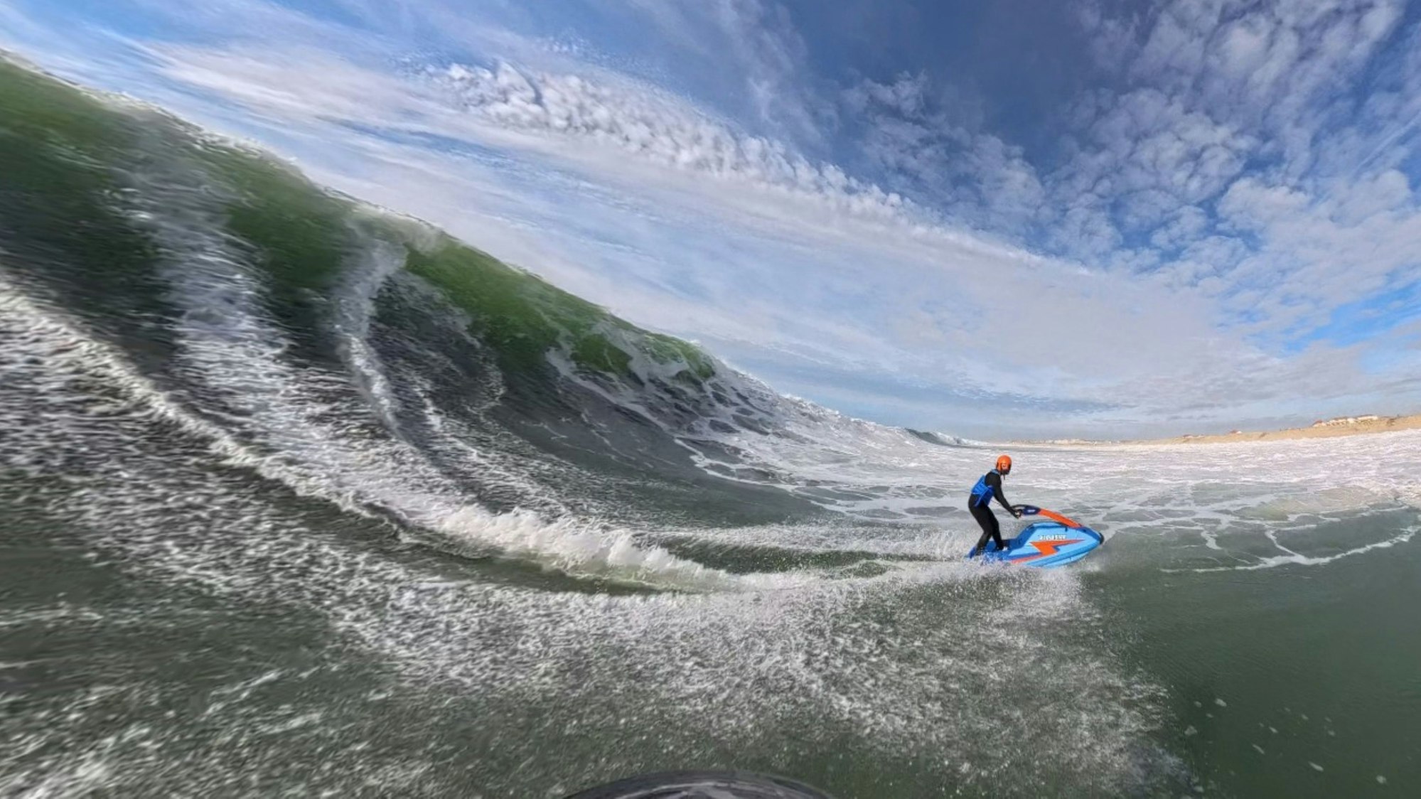 Zu sehen ist eine Jetski-Fahrerin mitten in einer riesigen Welle.
