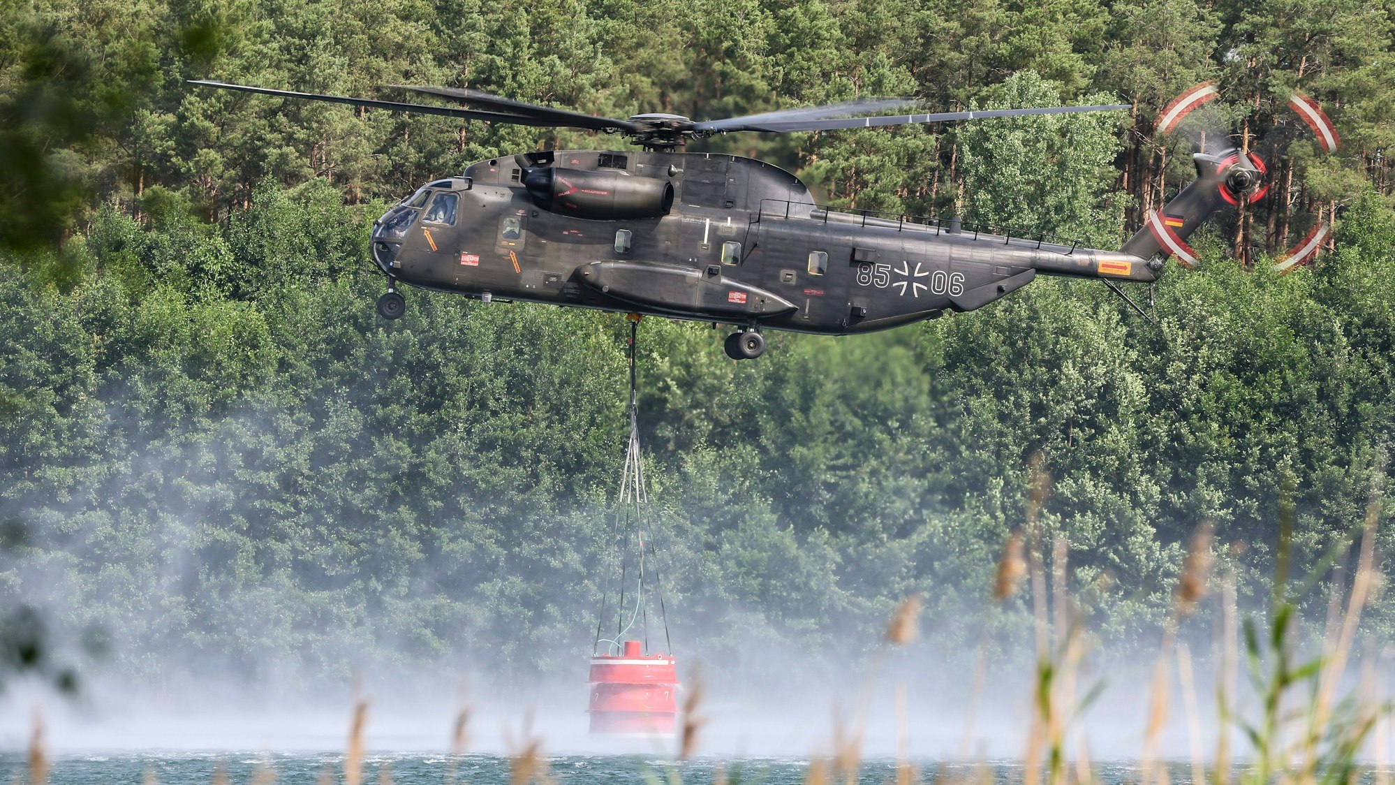 Ein Bundeswehrhubschrauber vom Typ Bell CH-53 holt Löschwasser zur Waldbrandbekämpfung aus dem Kiebitzer Baggerteich. (Symbolbild)