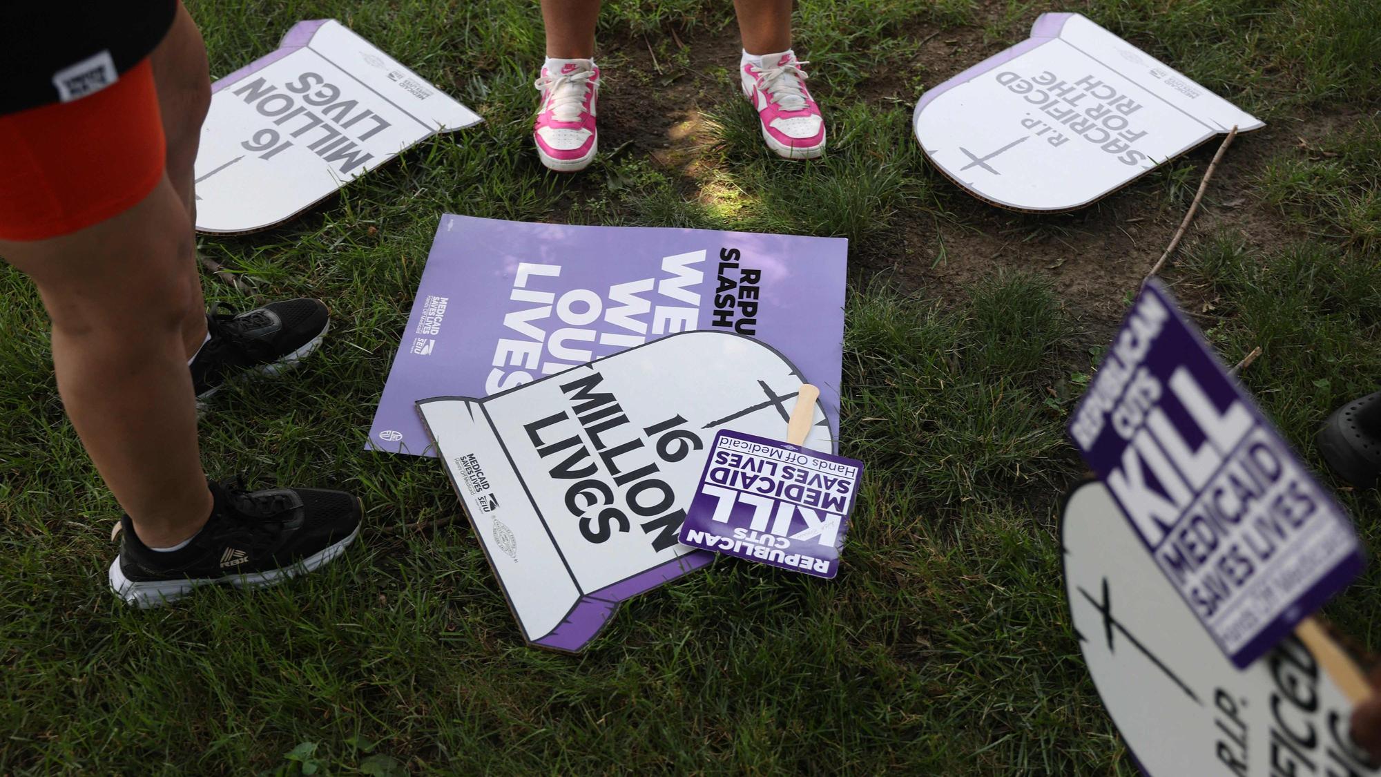 Schilder einer Demonstration gegen die Sozialkürzungen liegen auf einer Wiese in Washington.