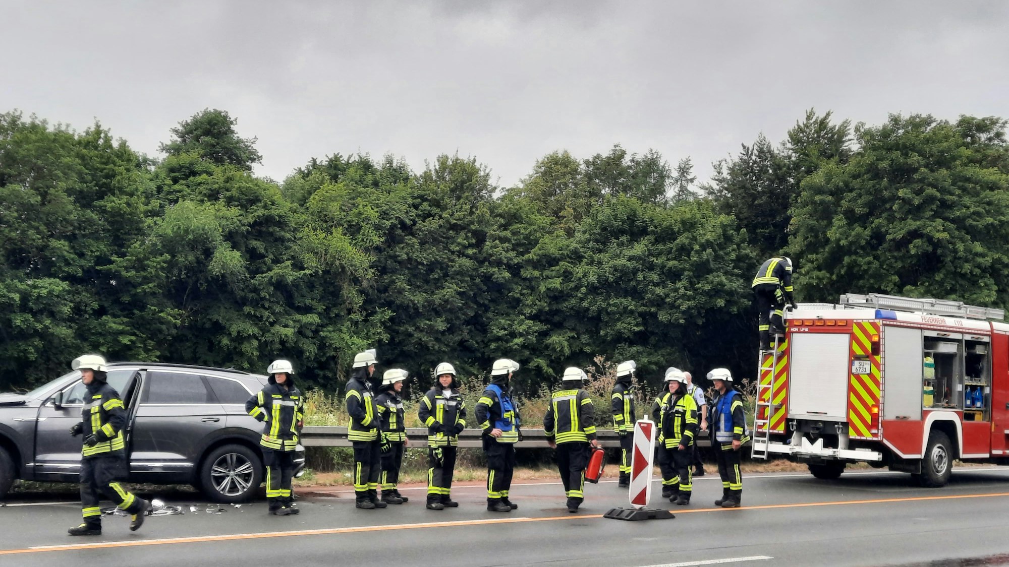 Feuerwehrleute neben einem Unfallwagen auf der Autobahn.