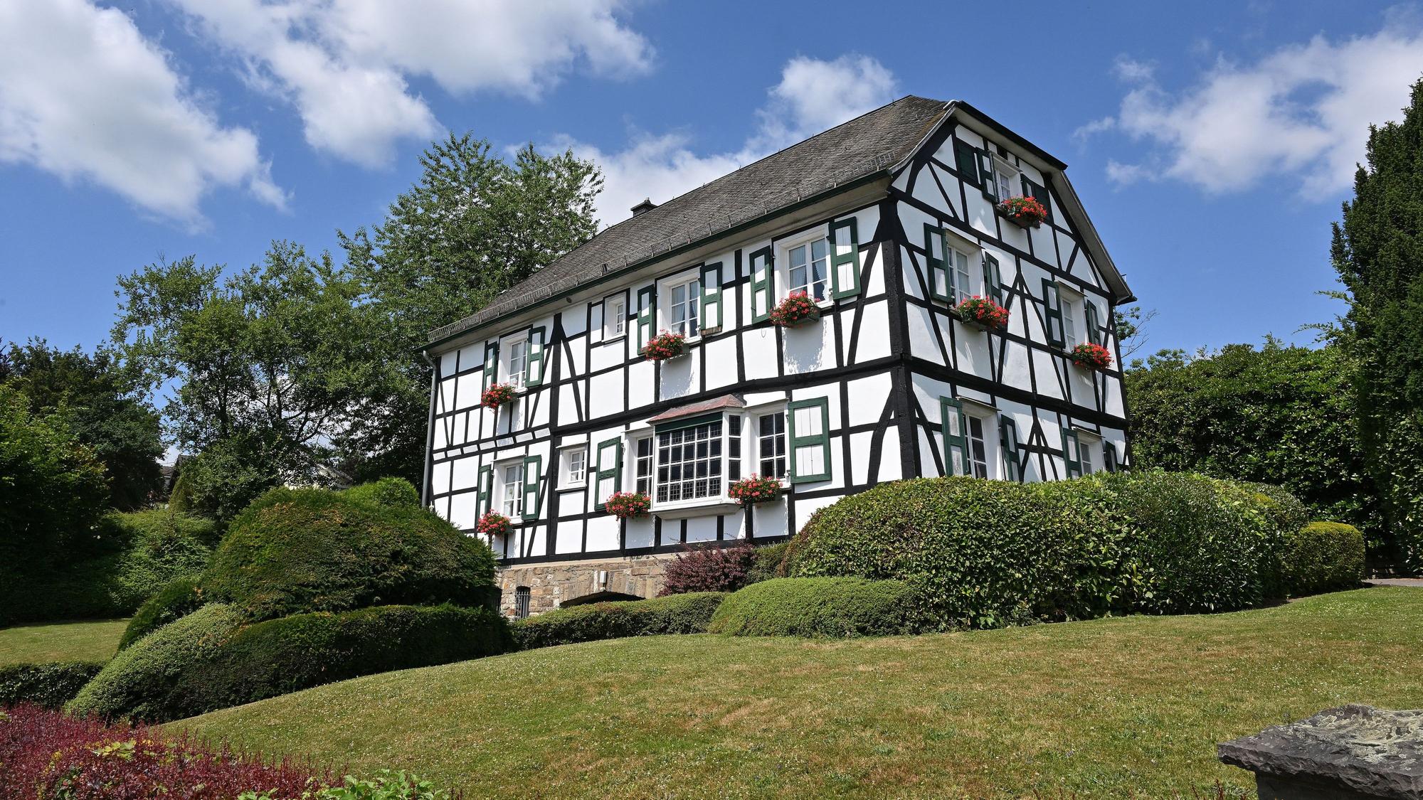 Das Alte Pastorat, ein historisches Fachwerkhaus, ist umringt von Hecken und Büschen.