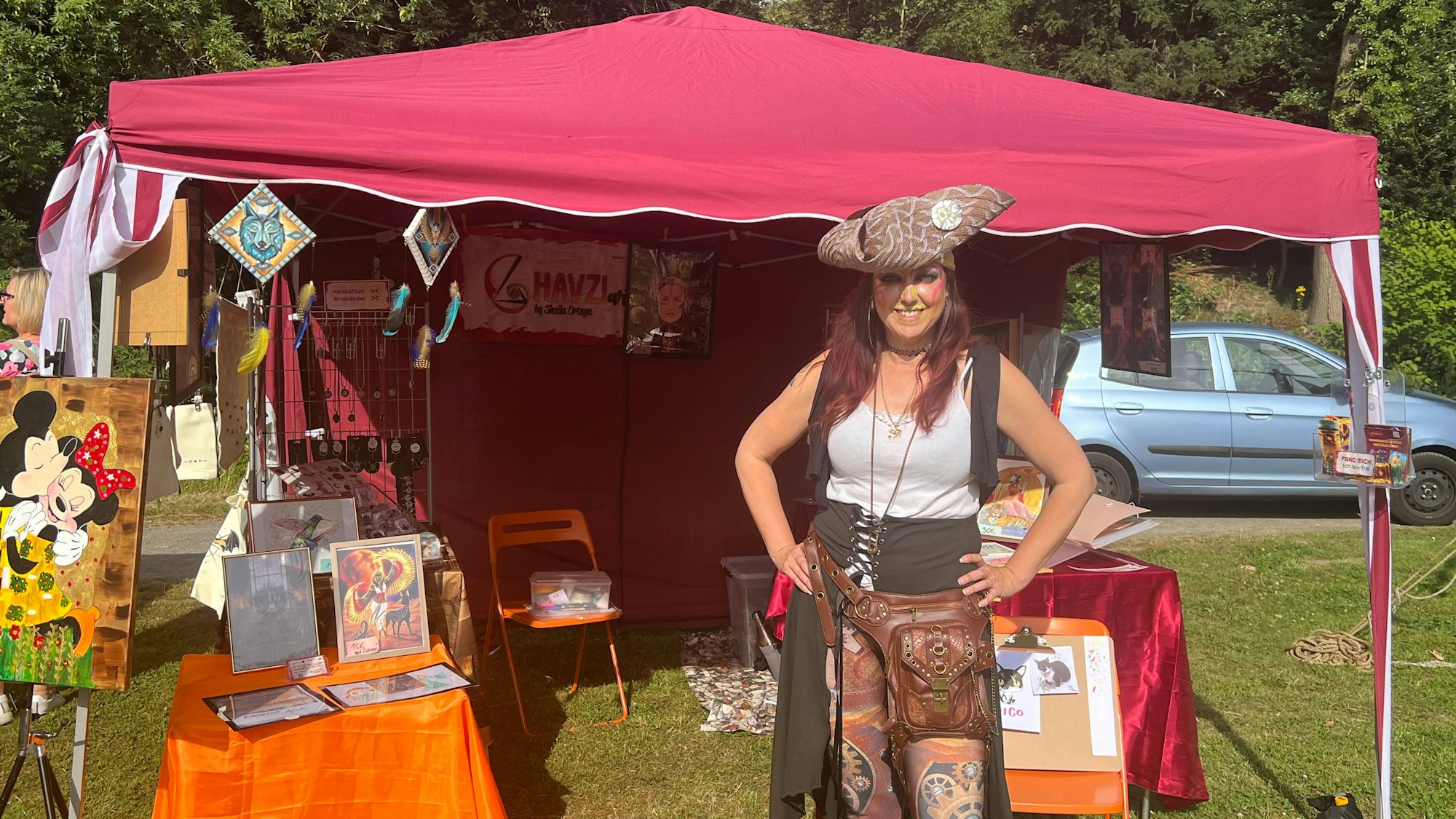 Eine verkleidete Künstlerin steht an einem Stand.