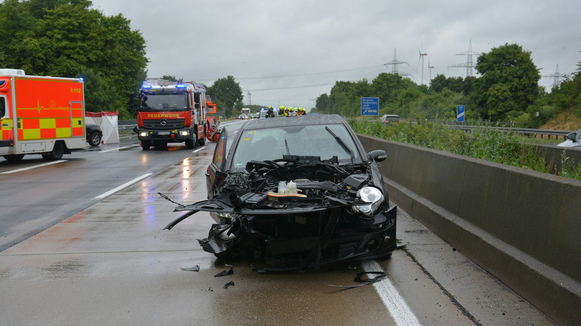 Das Foto zeigt ein schwer beschädigtes Auto sowie Einsatzfahrzeuge der Feuerwehr auf der Autobahn.