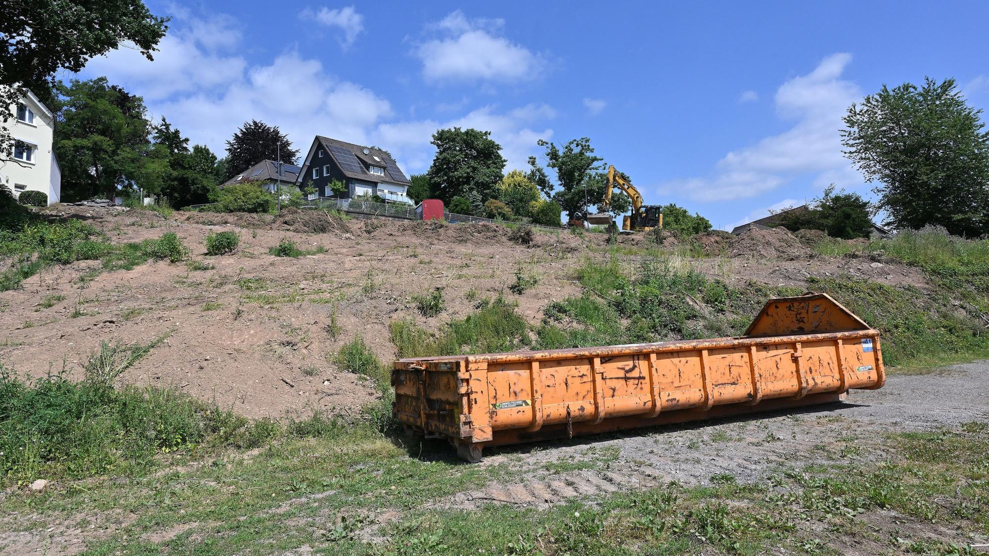 Auf dem Grundstück, auf dem gebaut werden soll, steht ein orangefarbener Container.